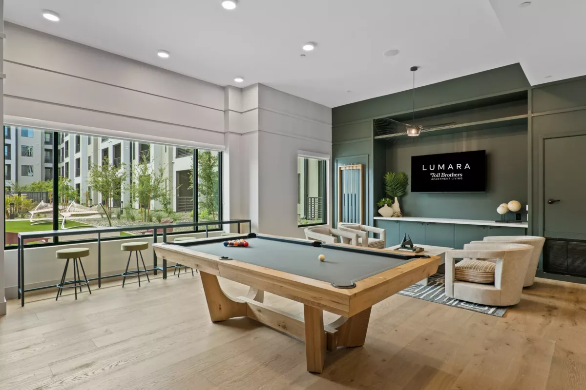 Recreation room with pool table, lounge chairs, and large window overlooking exterior landscaping.