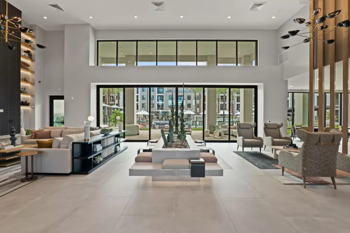 Modern lobby with lounge seating, tile floors, and large windows overlooking outdoor amenities.