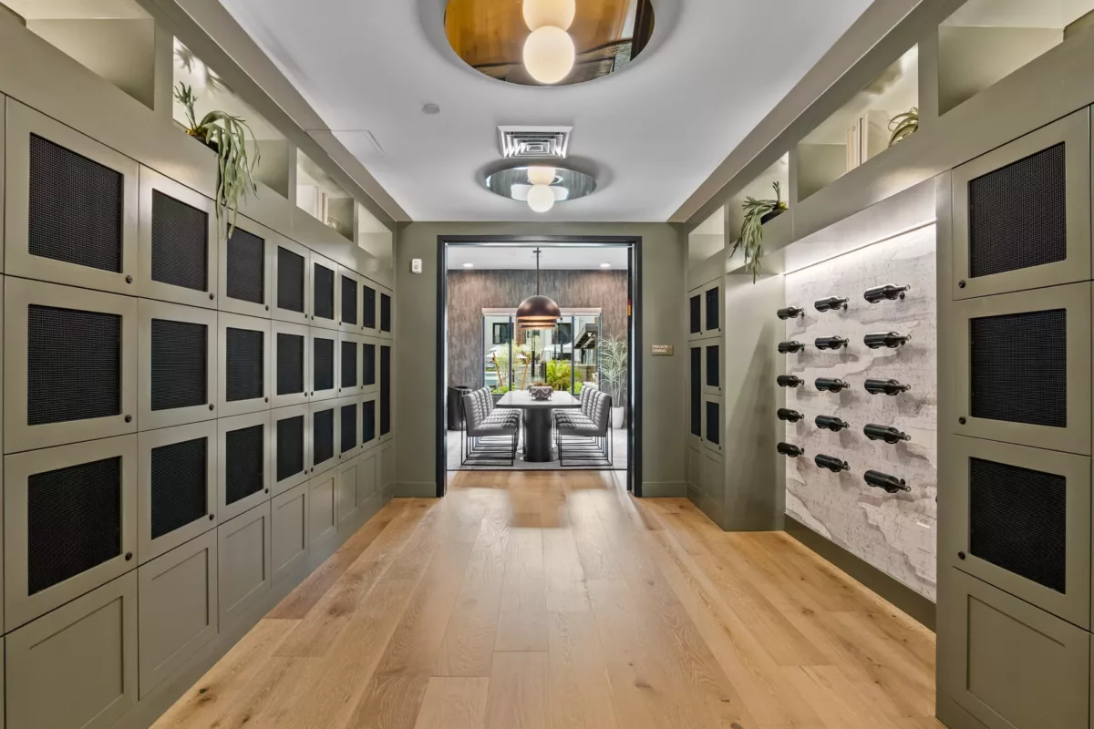 Hallway with lockers, wine storage, and view into private dining room with table and chairs.