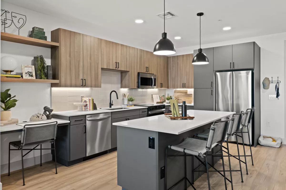 Modern kitchen with gray cabinets, wood accents, white countertops, island with seating, and...