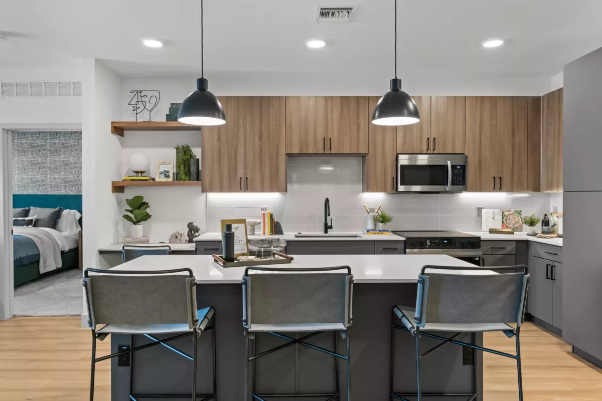 Modern kitchen with island, white countertops, wood and gray cabinets, and pendant lighting.
